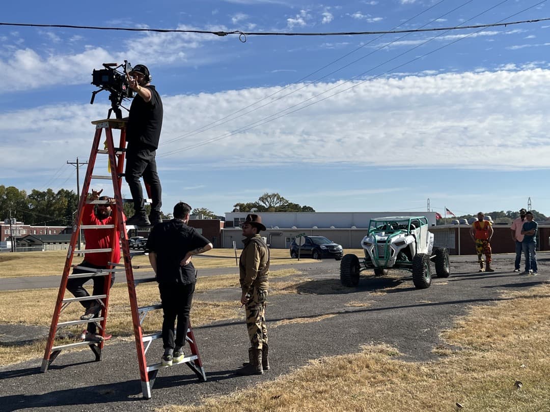 Behind the scenes photo 47 from Clone Cops production showing cinematographer corey allen, gaffer barrett dennison, 1st ad nate eggert, and 2nd ad nick wagner prepare for a shot with a ladder pod